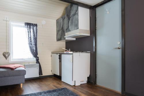 a small kitchen with a refrigerator and a window at Aurora River Camp Glass igloos & cabins in Kiruna