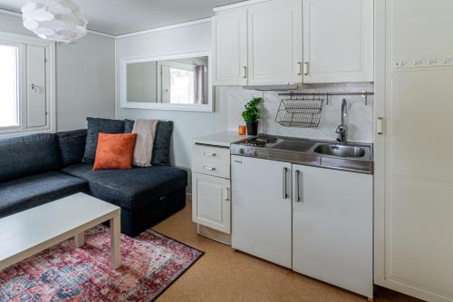 a kitchen and living room with white cabinets and a couch at Aurora River Camp Glass igloos & cabins in Kiruna
