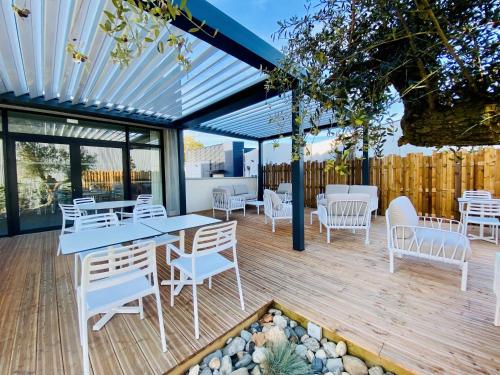 un patio con tavoli e sedie bianchi su una terrazza in legno di COURRIER SUD a Quint-Fonsegrives
