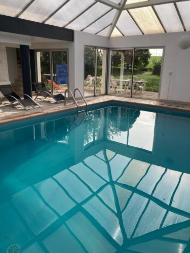 a swimming pool with blue water and windows at Gîte familial avec spa privatif & piscine chauffée in Belleray