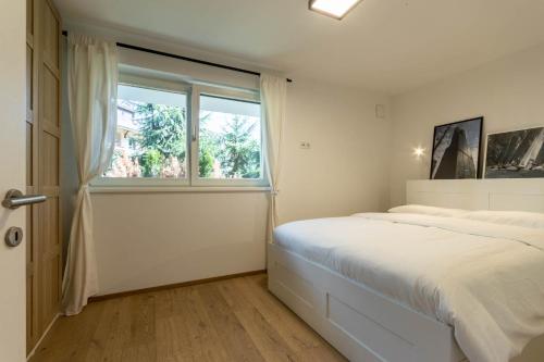 um quarto branco com uma cama e uma janela em Casa Fiammetta em Brunico