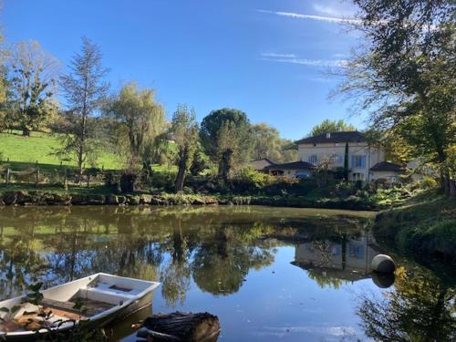 un barco sentado en un río con una casa en CHAMBRES DES EAUX 28 "baptistine", en Sarcey