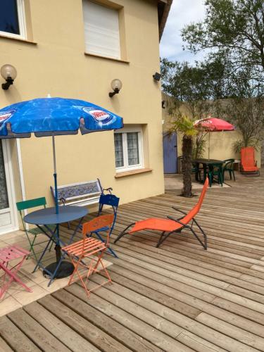 une table, des chaises et un parasol sur une terrasse dans l'établissement Le Robinson, à Marseillan