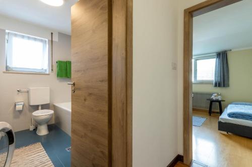 een badkamer met een toilet, een bed en een deur bij Casa Waldheim in Brunico