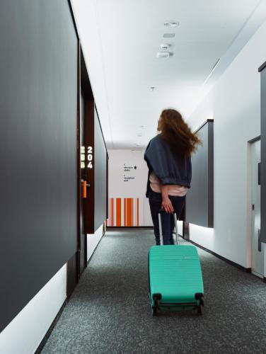a woman walking down a hallway with a green suitcase at City Inn Lviv Smart Hotel in Lviv