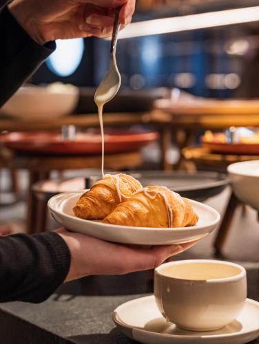 a person holding a plate of croissants with a fork at City Inn Lviv Smart Hotel in Lviv