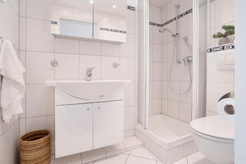 La salle de bains blanche est pourvue d'un lavabo et d'une douche. dans l'établissement Haus Meeresblick Wohnung 80, à Kellenhusen