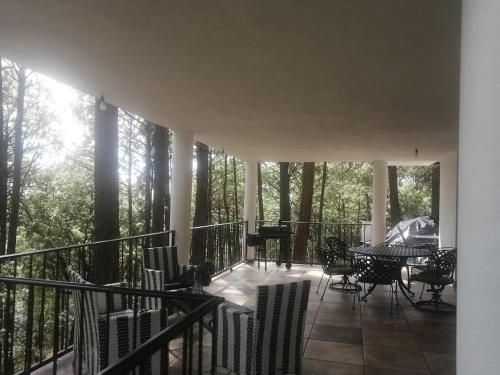 einen Balkon mit Stühlen, einem Tisch und einem Klavier in der Unterkunft Cabaña D' Leon in Mazamitla