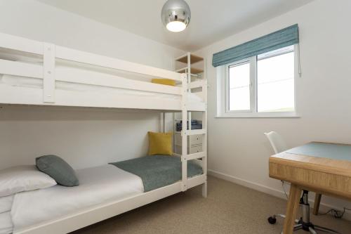 a bedroom with two bunk beds and a desk at CROYDE PEBBLES 4 Bedrooms in Croyde