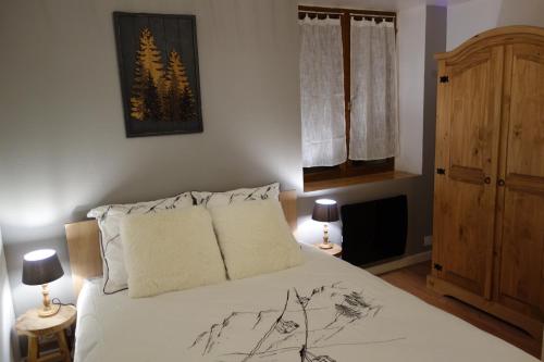 um quarto com uma cama com lençóis brancos e 2 candeeiros em Chez petit Louis- Appart centre ville jusqu'à 6 personnes em Briançon