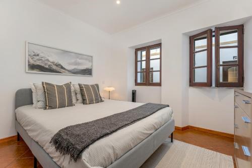 - une chambre avec un grand lit blanc et des fenêtres dans l'établissement Casa dos Sonhos Albufeira, à Albufeira
