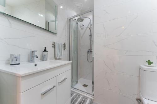 une salle de bain blanche avec une douche et un lavabo dans l'établissement Casa dos Sonhos Albufeira, à Albufeira