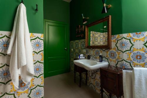Baño verde con lavabo y espejo en Frangimare La Segreta, en Malfa