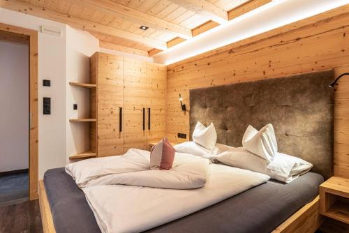 a large bed in a room with a wooden wall at Zu Grof Alpenglühn in Castelrotto