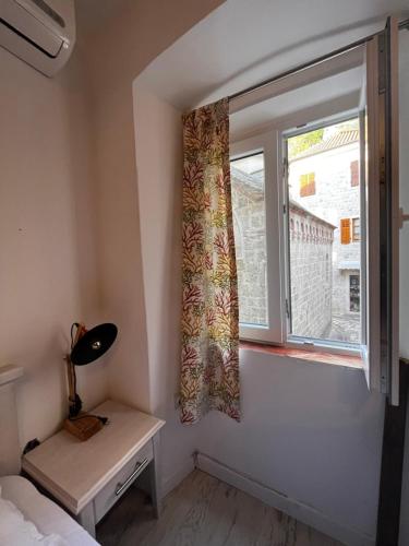 a small bedroom with a window and a desk at Athos Guesthouse in Kotor