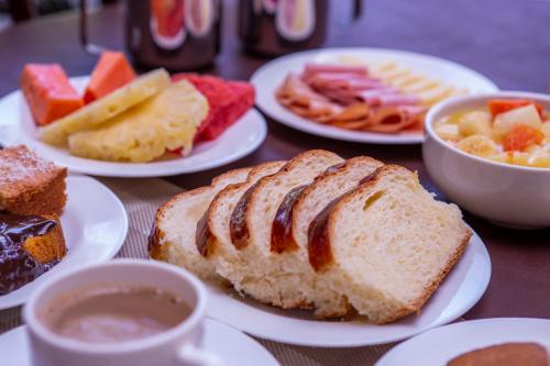 a table topped with plates of bread and bowls of fruit at Ciribaí Praia Hotel in Pauba