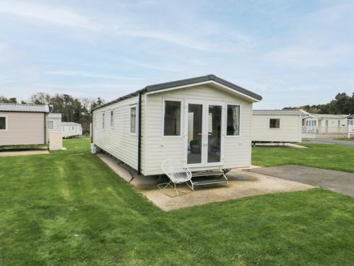 a white tiny house with a chair in a yard at Pines 30 in Scarborough