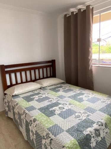 um quarto com uma colcha numa cama com uma janela em Apartamento Apês do Peró 10 - centro - 5 pessoas em Cabo Frio