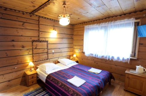 1 dormitorio con 1 cama en una cabaña de madera en Agroturystyka Chmiel en Sromowce Wyżne