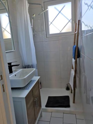 une salle de bain blanche avec un lavabo et une fenêtre dans l'établissement Le Mabileau, à Saumur