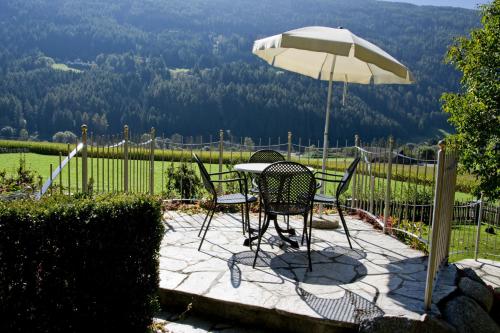 a table and chairs under an umbrella on a patio at Residence Obermoarhof - Family Apartments with Pool & Playground in Vandoies