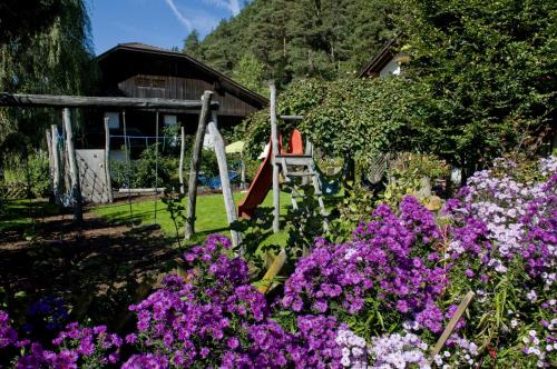 a garden with purple flowers in front of a house at Residence Obermoarhof - Family Apartments with Pool & Playground in Vandoies