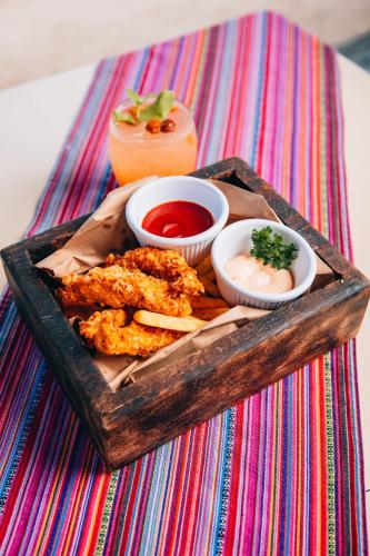a wooden tray with fried foods and sauces on a table at Umaya Resort & Adventures in Maya Beach