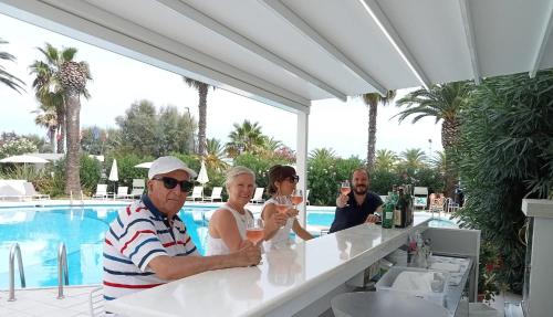 a group of people sitting at a bar near a pool at International Hotel & Suite in San Benedetto del Tronto
