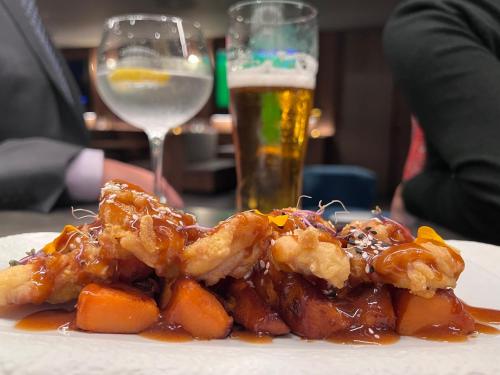 a plate of food with shrimp and carrots and a glass of beer at BAH Barcelona Airport Hotel in El Prat de Llobregat