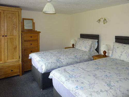 a bedroom with two beds and a dresser at Glan Wye in Rhayader