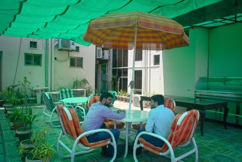 two men sitting at a table under an umbrella at Premier Inn Grand Gulberg Lahore in Lahore