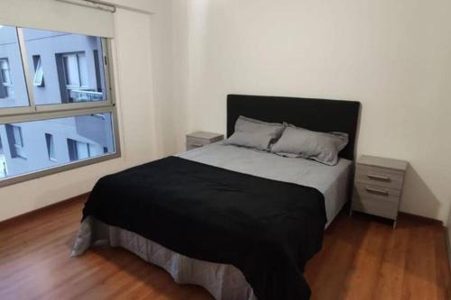 1 dormitorio con cama negra y ventana en Lujoso departamento con Pileta en Villa Crespo- Camargo en Buenos Aires