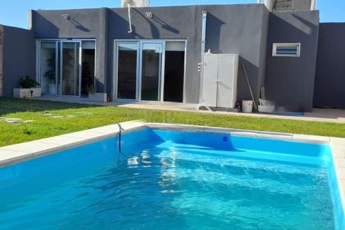 a blue swimming pool in front of a house at Casa con pileta mirador de cabildo in La Punta