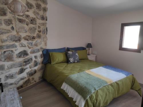Ce lit se trouve dans un dortoir doté d'un mur en pierre. dans l'établissement Casa el Recreo, à Jérica