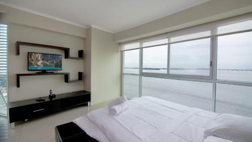 1 dormitorio con cama grande y ventana grande en Riverfront I 2, piso 4, suite vista al rio, Puerto Santa Ana, Guayaquil, en Guayaquil