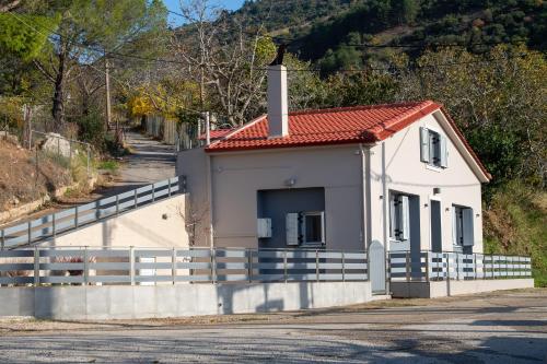 a small white house with a fence next to a road at Summit Guest House in Kalavrita