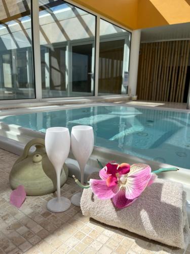 - une piscine avec deux verres à vin et une fleur dans l'établissement Résidence Hôtelière Natureva & Spa, au Cap d'Agde