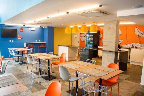 a restaurant with wooden tables and orange chairs at Ibis Styles Garanhuns in Garanhuns