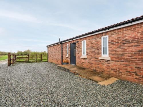 a brick building with a door and a fence at The Apple Shed in Wisbech