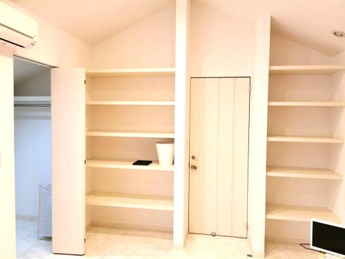 a closet with white shelves and a door at Bell house in Tokyo