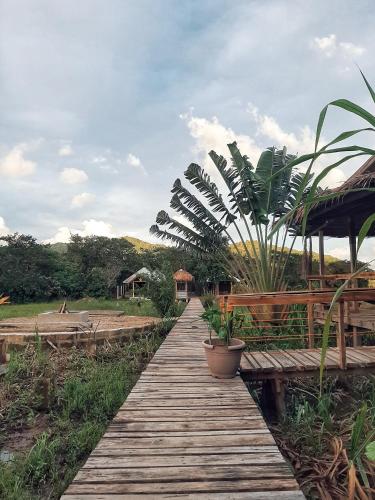 a wooden walkway with potted plants on it at Cabanas de Nacpan Camping Resort in El Nido