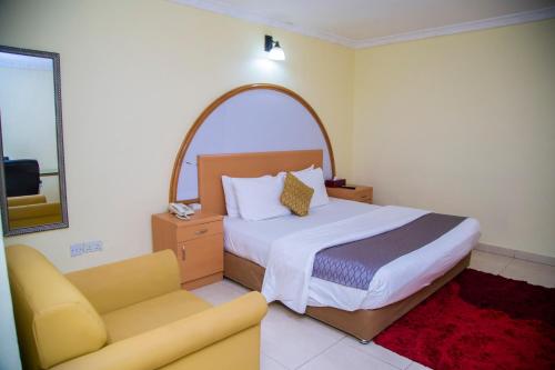 a bedroom with a bed and a chair and a couch at Airside Hotel in Accra