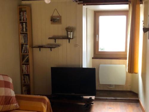 a living room with a flat screen tv and a window at Casetta AnnyCa in Bourg-Saint-Pierre