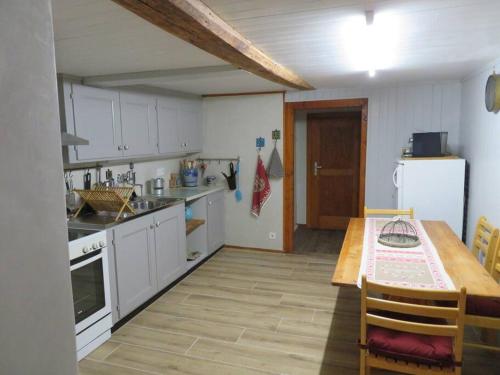 eine Küche mit weißen Schränken, einem Tisch und einem Esszimmer in der Unterkunft Casetta AnnyCa in Bourg-Saint-Pierre
