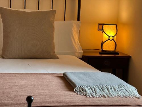 Cama con almohada y lámpara en mesita de noche en Corzo Hotel, en Cercedilla