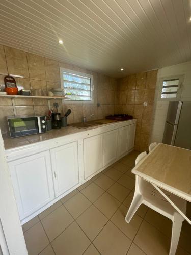 a kitchen with white cabinets and a sink and a table at La perle créole in Lamentin
