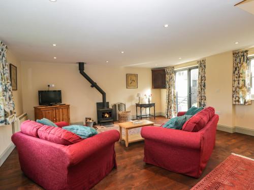 a living room with two red chairs and a fireplace at Nine Acres Barn in Marlborough