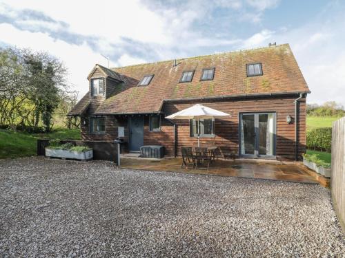 a brick house with a patio and an umbrella at Nine Acres Barn in Marlborough