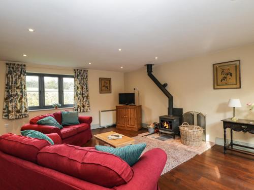 a living room with two red couches and a fireplace at Nine Acres Barn in Marlborough