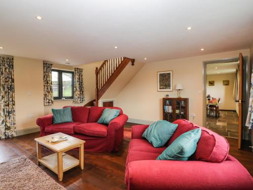 a living room with two red couches and a table at Nine Acres Barn in Marlborough